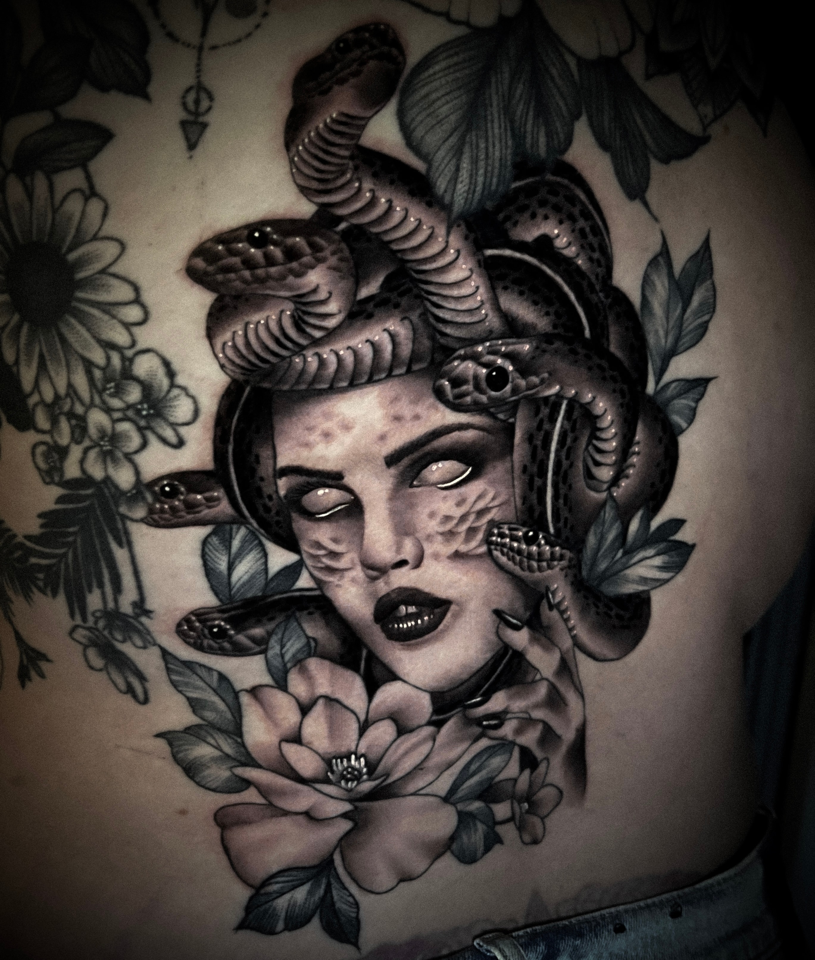 Demonic face with serpents and flowers tattoo by Steve Young